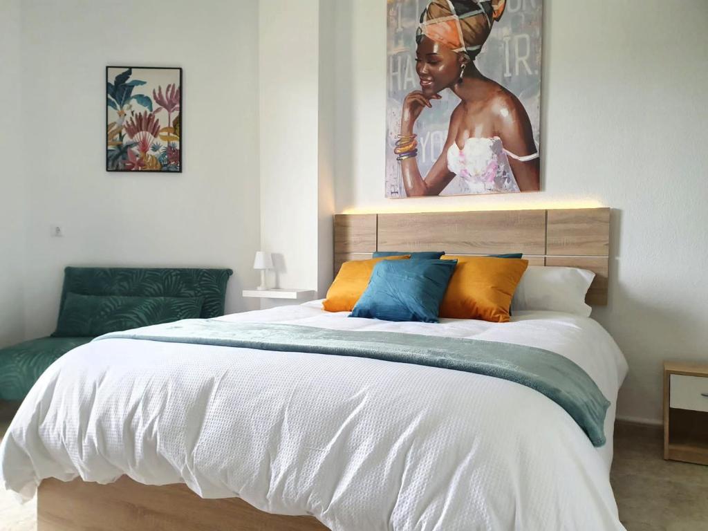 1 dormitorio con 1 cama con una pintura en la pared en Apartamento tropical con piscina cerca de la playa en Torremolinos