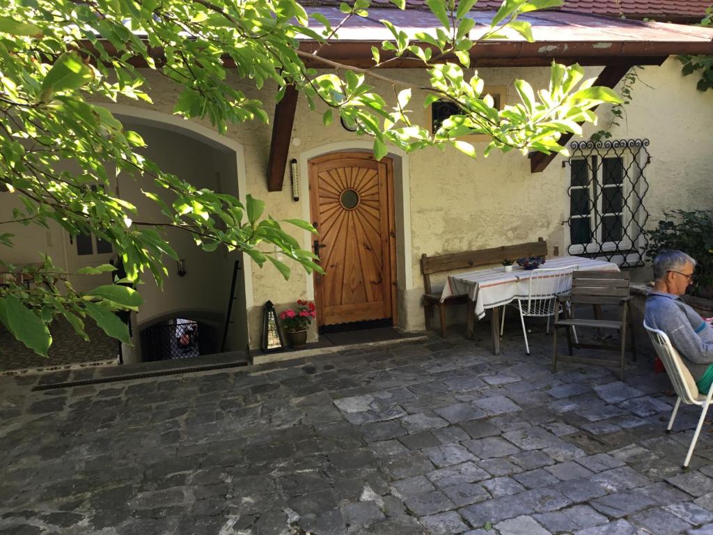 eine Person, die an einem Tisch vor einem Haus mit einer Holztür sitzt in der Unterkunft Altes Bürgerhaus in Dürnstein