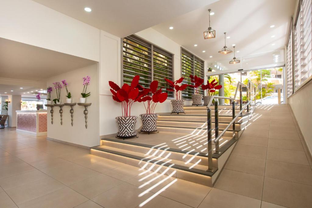 a lobby with a staircase with red flowers in vases at Olé Tropical Tenerife Adults Only in Playa de las Americas