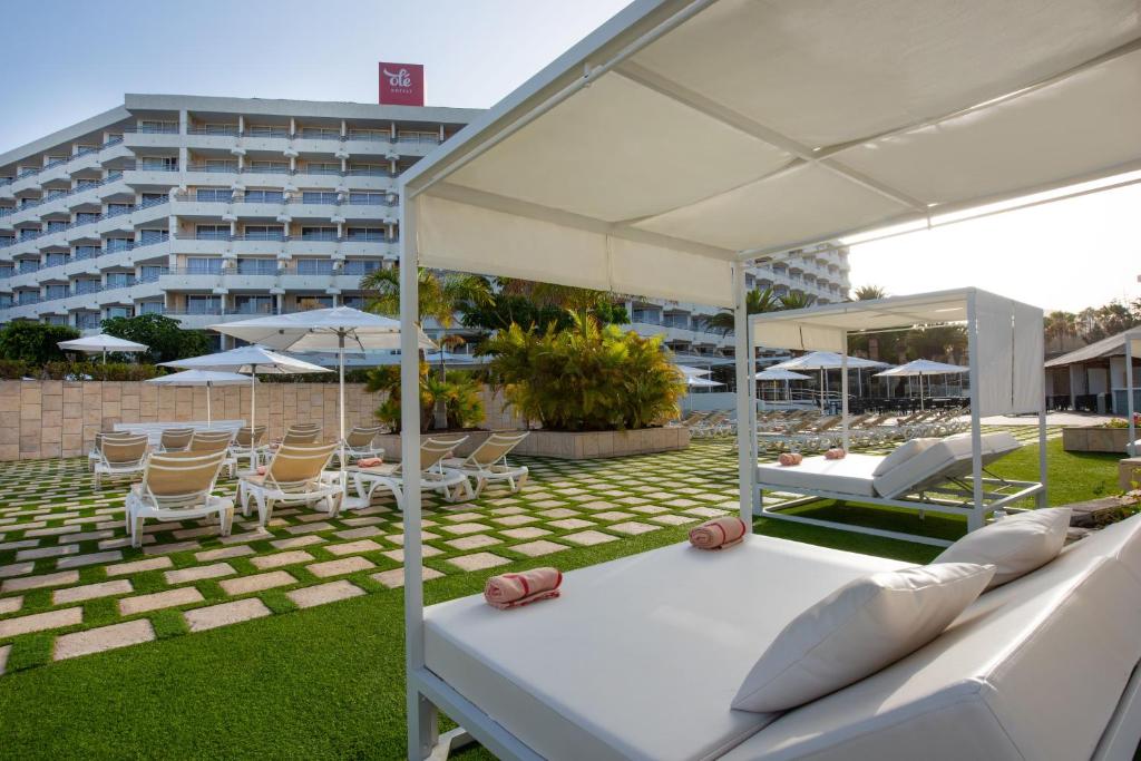a patio with chairs and beds and a building at Olé Tropical Tenerife Adults Only in Playa de las Americas