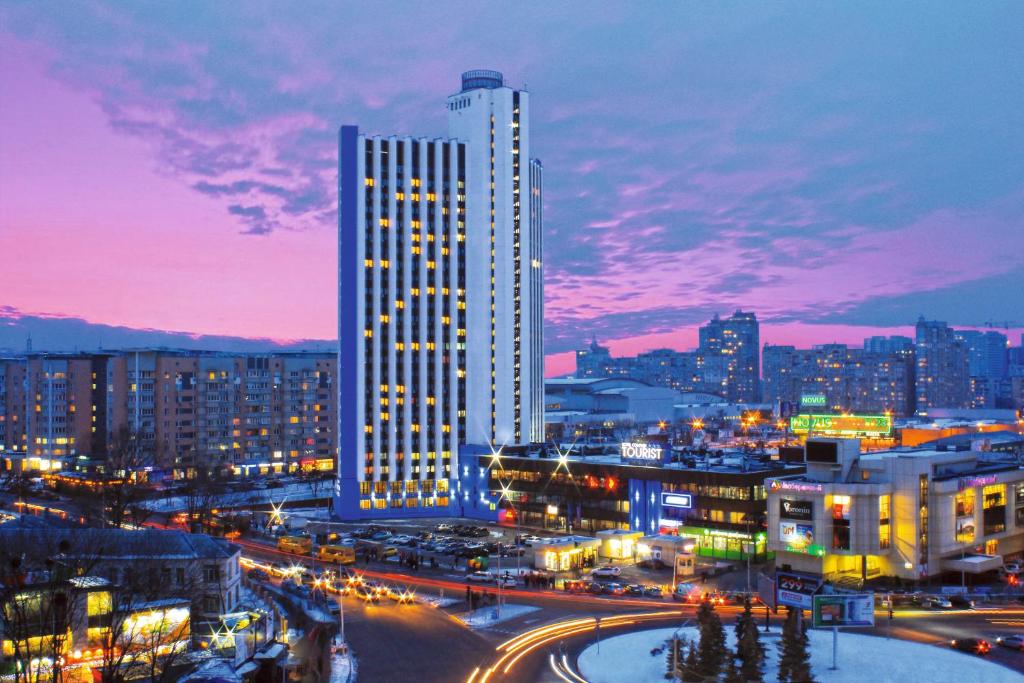 eine Skyline der Stadt in der Nacht mit einem hohen Gebäude in der Unterkunft Tourist Hotel Complex in Kiew