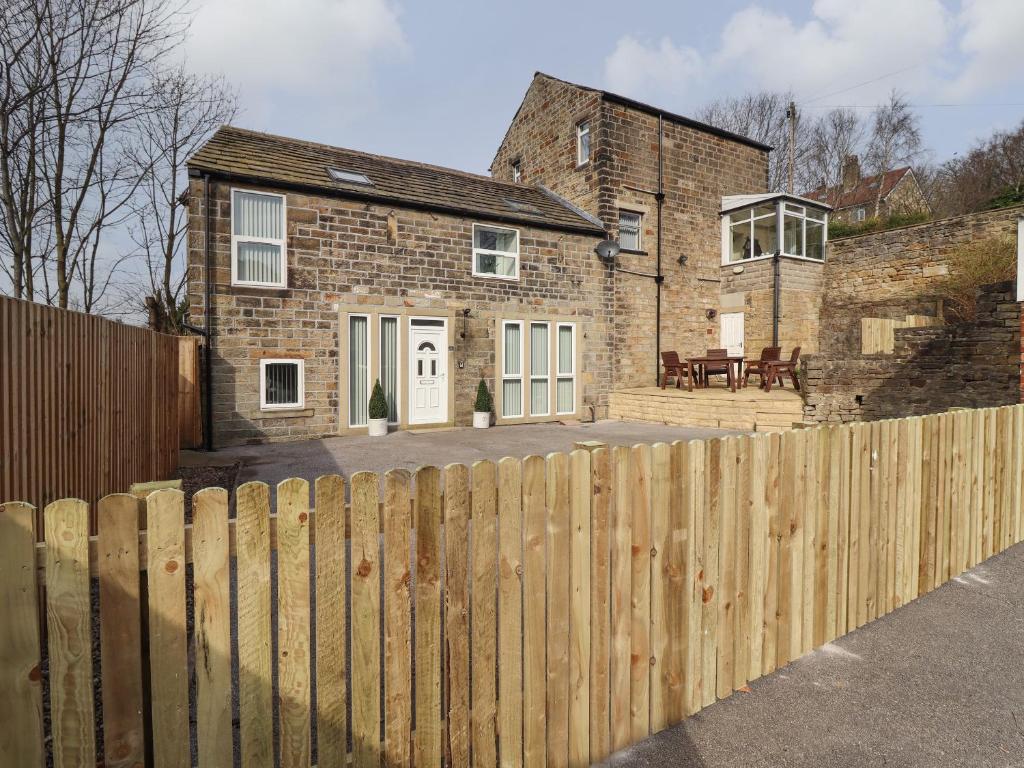 una casa con una valla de madera delante de ella en The Coach House, en Keighley