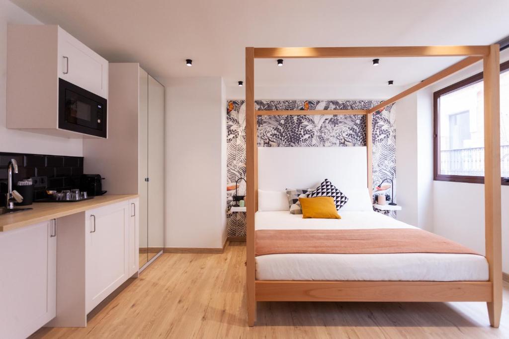 a bedroom with a canopy bed and a kitchen at Welldone Sierpes Boutique in Seville