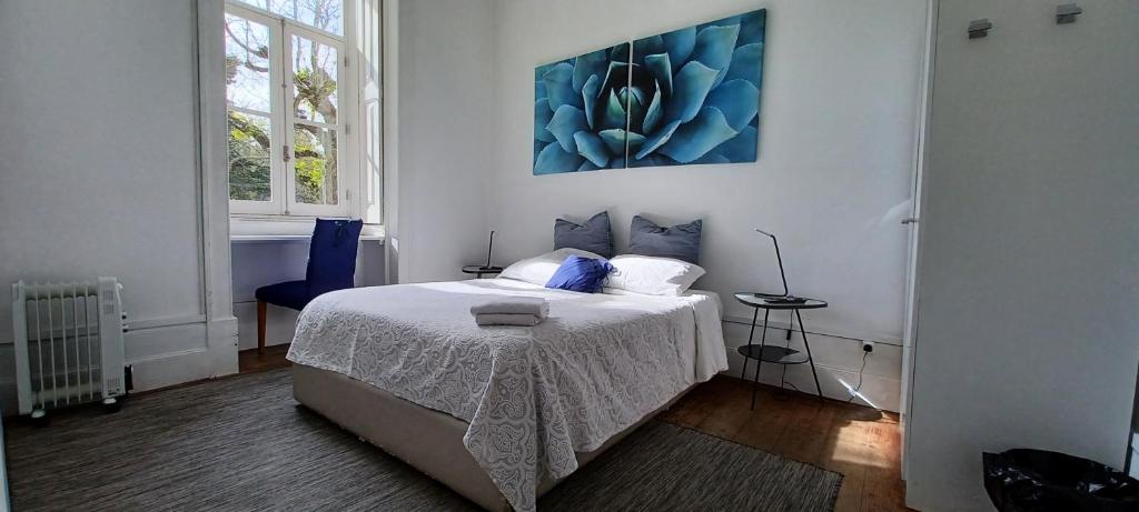 1 dormitorio con 1 cama y una pintura azul en la pared en WW Hostel & Suites en Coímbra