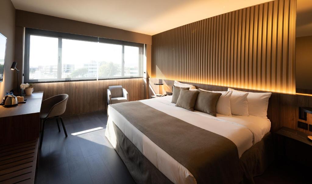 a hotel room with a bed and a desk and a window at BAH Barcelona Airport Hotel in El Prat de Llobregat