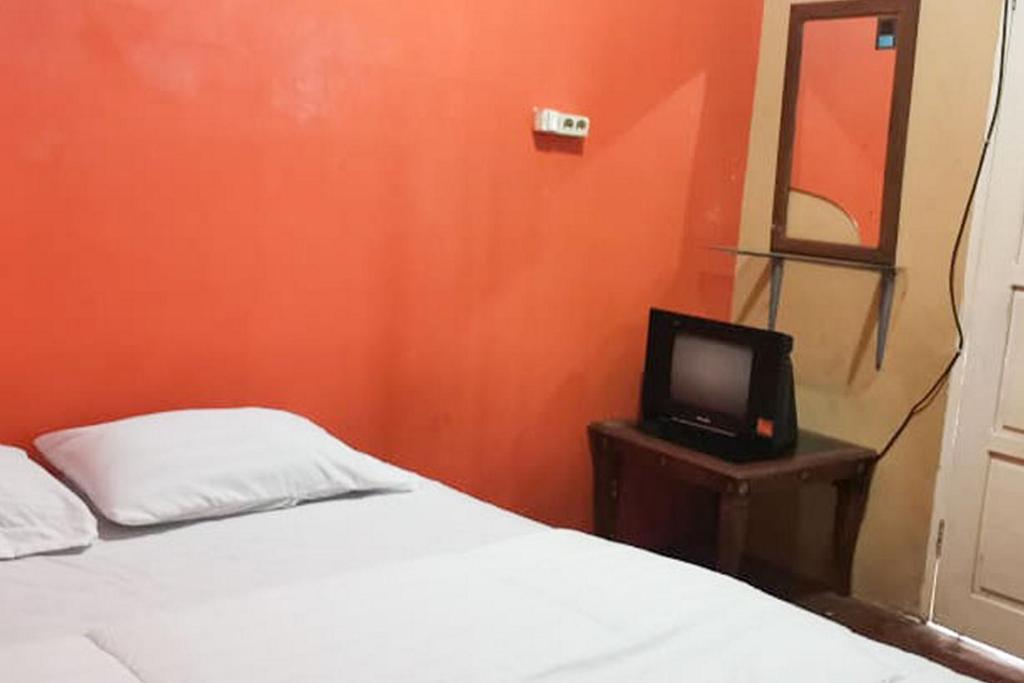 ein Schlafzimmer mit einem Bett und einem TV auf einem Tisch in der Unterkunft Oma Homestay Pagar Alam Syariah RedPartner in Pagaralam