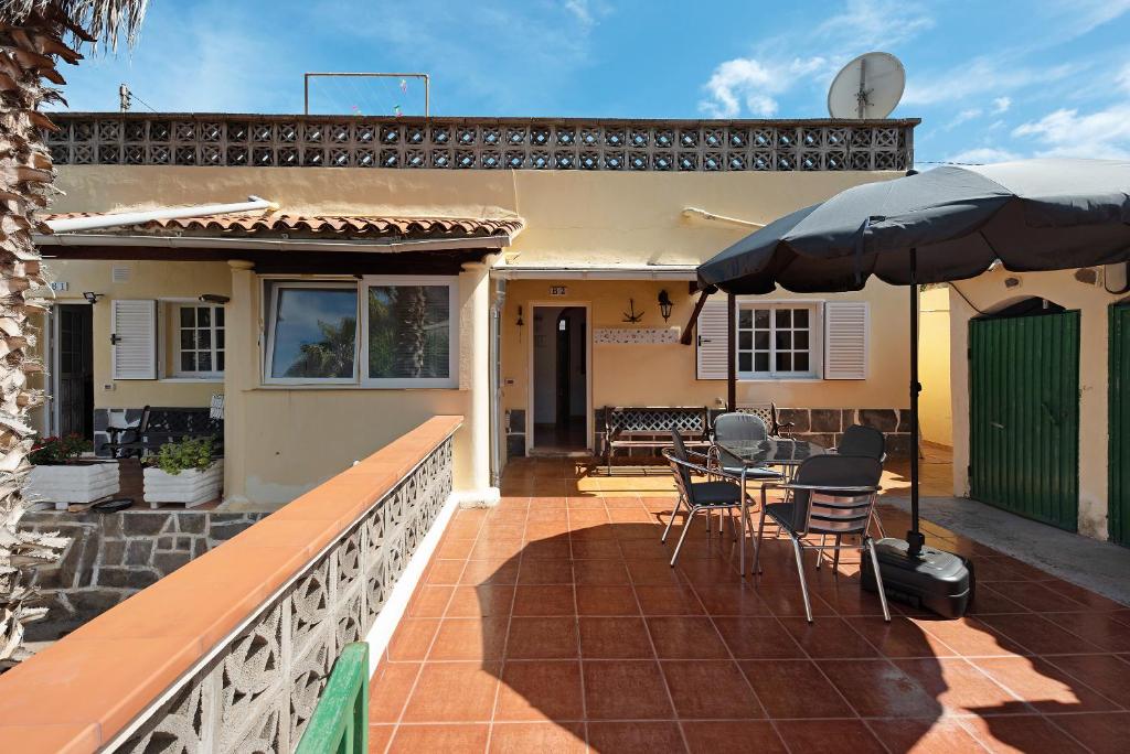 een huis met een patio met een tafel en een parasol bij Casa El Cardon B2 in Buenavista del Norte