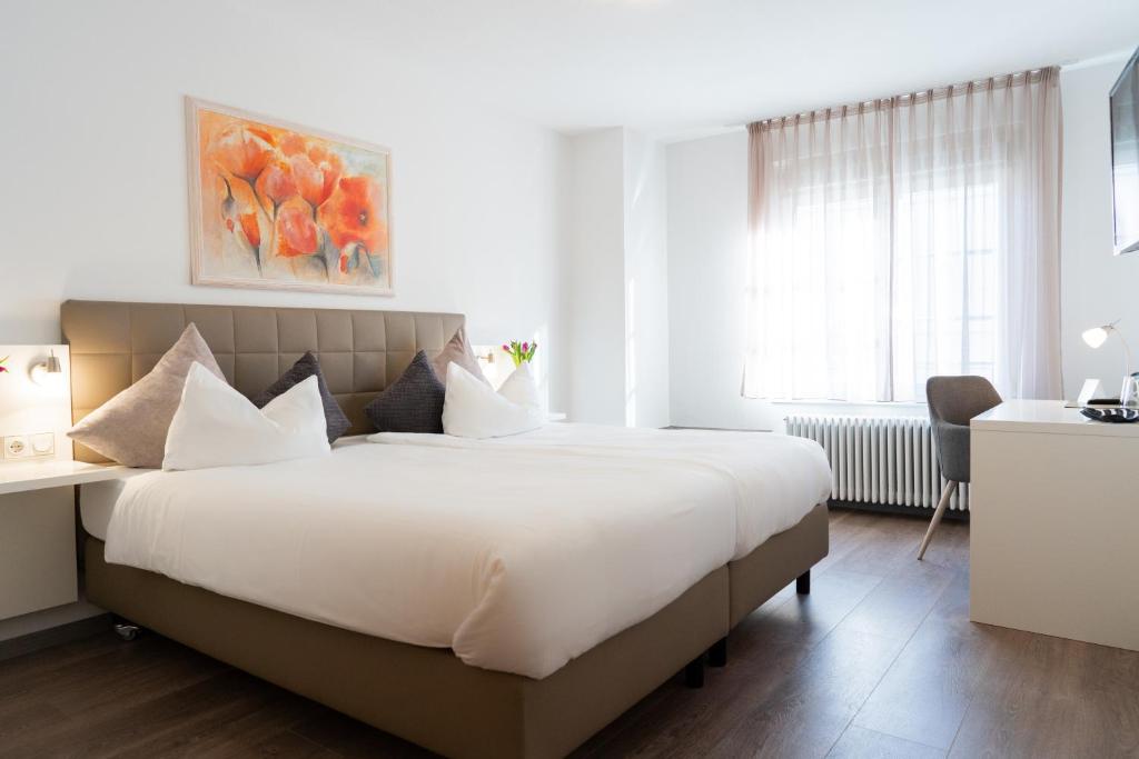 a bedroom with a large white bed and a desk at Hotel La Fleur in Überlingen