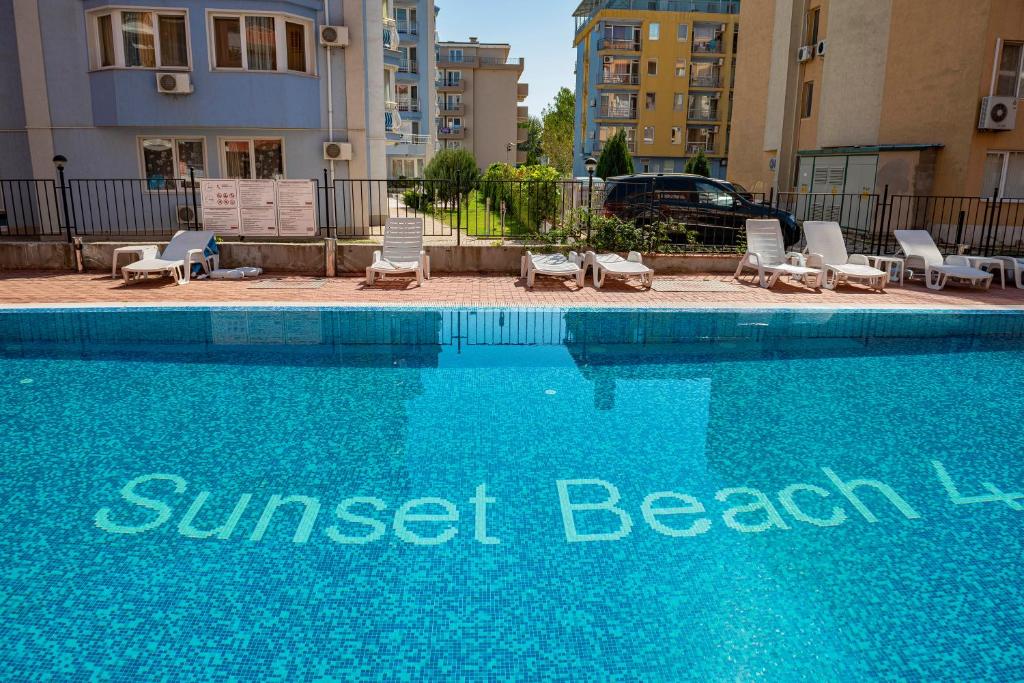 サニービーチにあるSunset Beach - Menada Apartmentsのスイミングプール(ラウンジチェア付)、ホテルの看板
