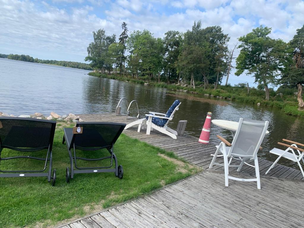un grupo de sillas sentadas en un muelle junto a un lago en Pärla med egen brygga en Västerås