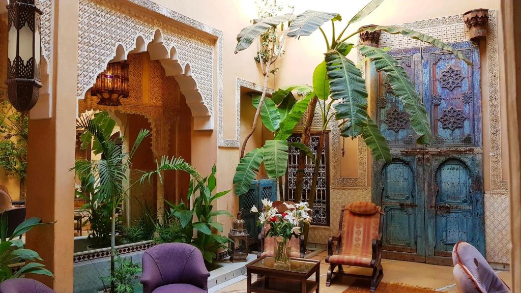 a room with chairs and plants in a building at Riad Armelle in Marrakesh