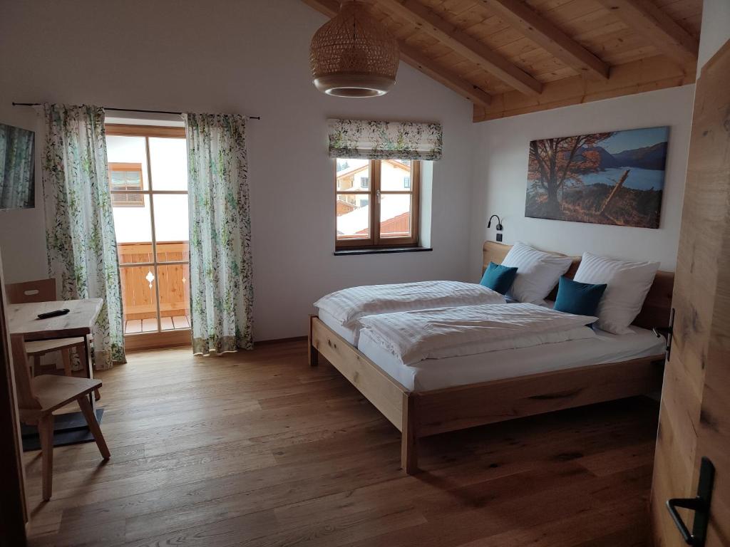 a bedroom with a bed and a desk and windows at Landhaus Hutter in Bad Heilbrunn