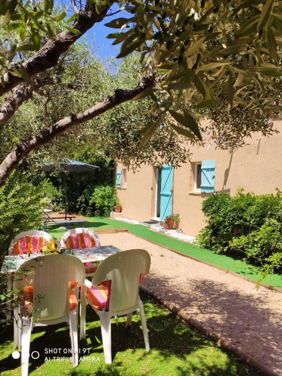une table et des chaises assises sous un arbre dans une cour dans l'établissement Appartement chaleureux à Cavalaire-sur-Mer 40 m² avec terrasse, à Cavalaire-sur-Mer