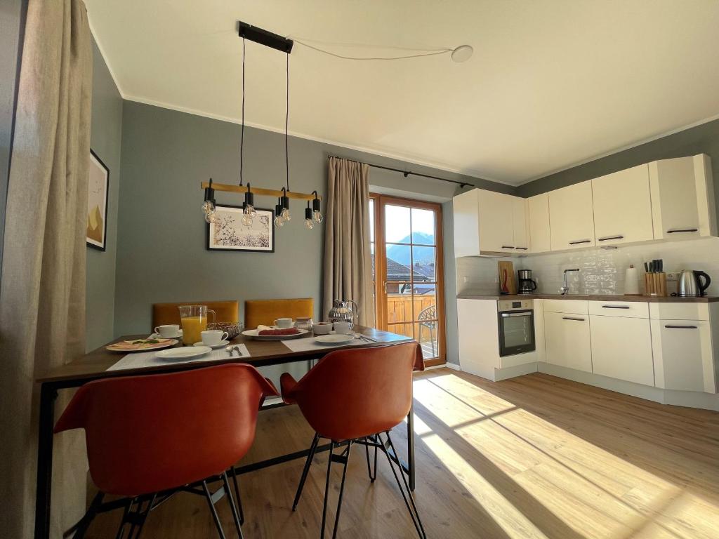 uma cozinha com uma mesa com cadeiras e uma sala de jantar em Das Bergquartier - Ferienwohnung Zugspitze em Oberau
