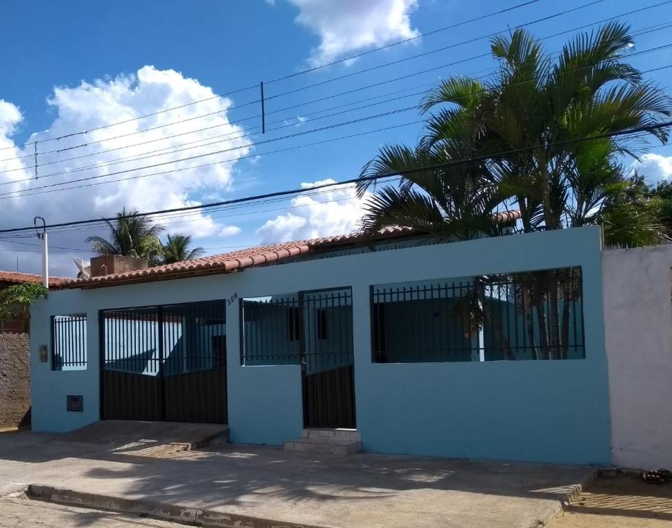 een wit huis met een poort en een palmboom bij Aluguel Temporada em Martins/RN in Martins