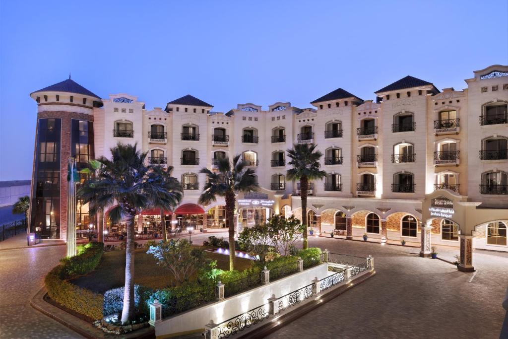 un grand bâtiment avec des palmiers devant lui dans l'établissement Crowne Plaza Riyadh Al Waha, an IHG Hotel, à Riyad