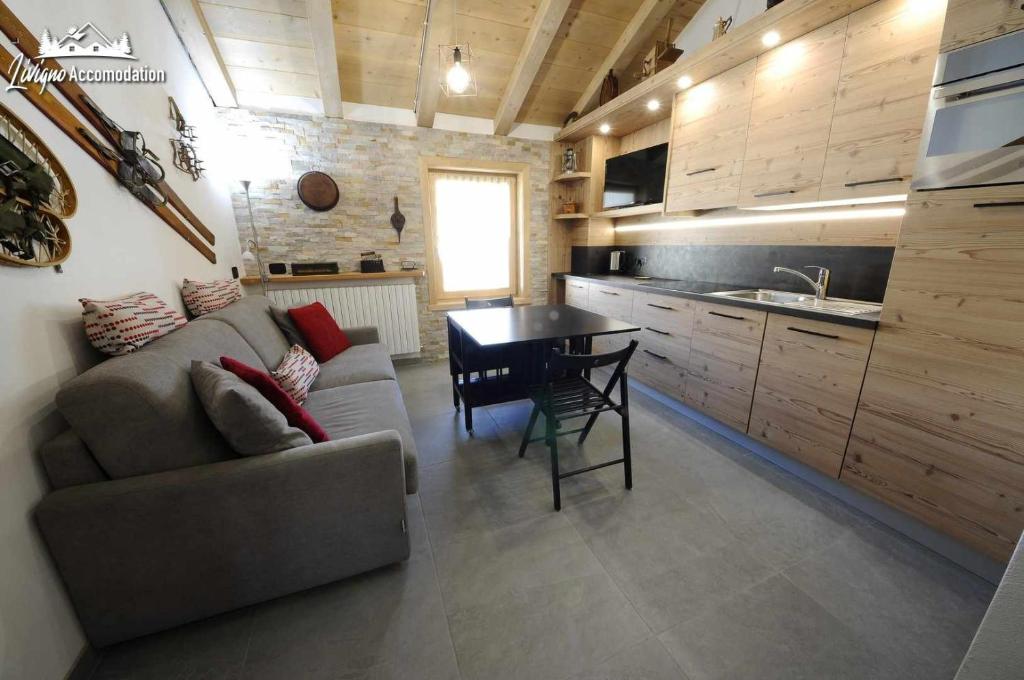 uma sala de estar com um sofá e uma mesa numa cozinha em Baita Carosello Apt 6 Appena rinnovato em Livigno