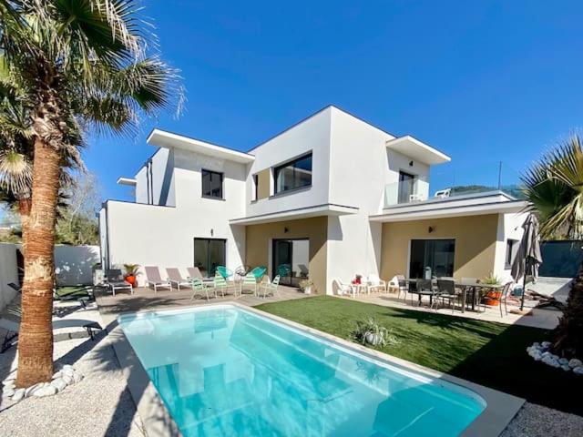une grande maison blanche avec une piscine devant dans l'établissement VILLA D’ARCHITECTE À 400M DE LA PLAGE, au Cap d'Agde