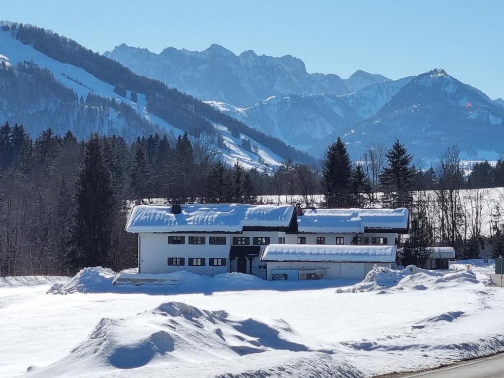 a building in the snow with mountains in the background at Zollhaus 65 in Reit im Winkl