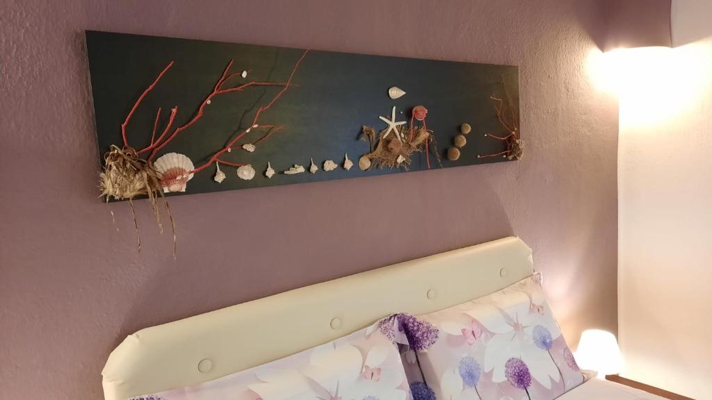 a picture hanging above a bed in a room at Villa Kuky in Santa Teresa Gallura