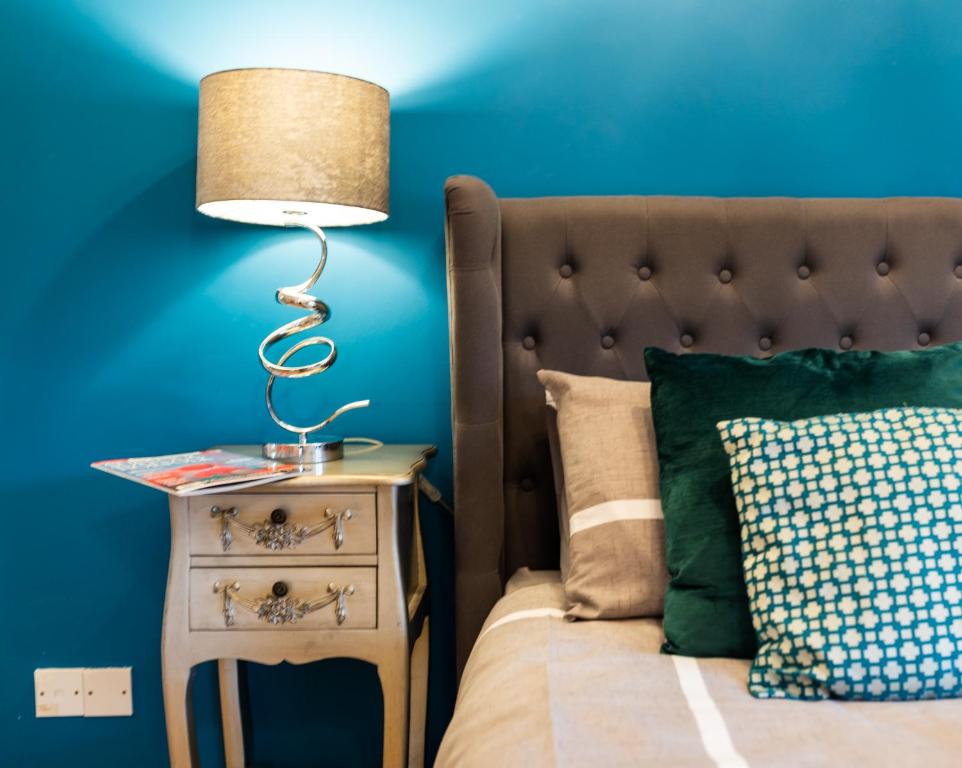 a lamp on a nightstand next to a bed at Church View - Norfolk Cottage Agency in Burnham Market