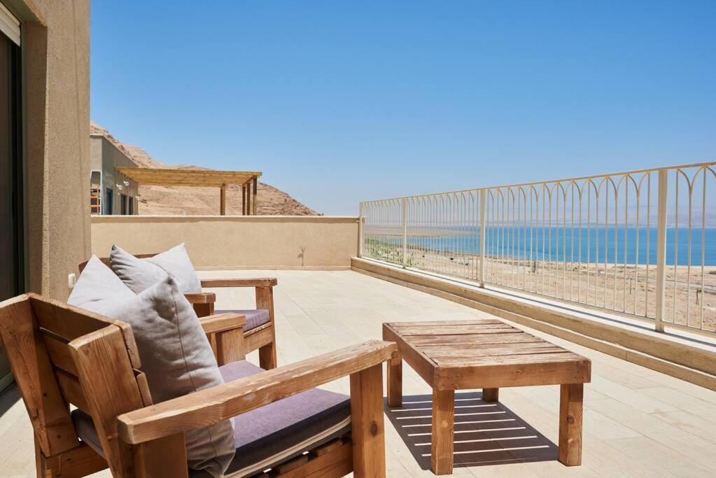 a balcony with two chairs and a table and the ocean at Beautiful home on the dead sea! in Ovnat