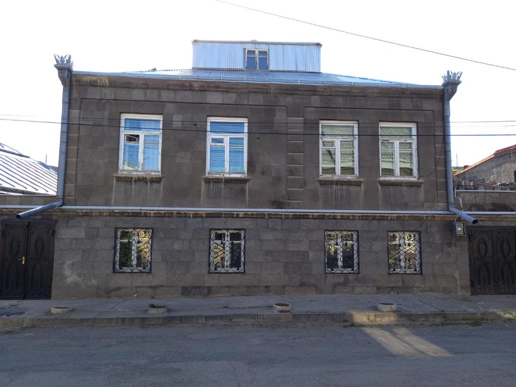 an old brick building with blue windows on a street at H.A.S.K in Gyumri