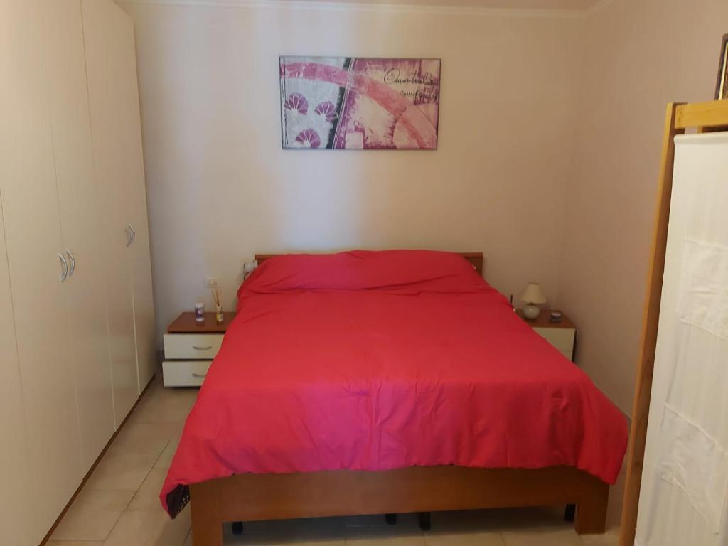 薩薩里的住宿－Appartamentino con cortile, Sassari Centro Storico，一间卧室配有红色的床和2个床头柜