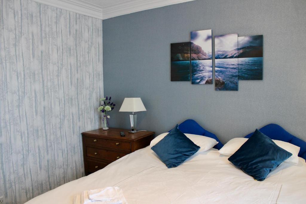 a bedroom with a bed with four paintings on the wall at Bryn Noddfa in Morfa Nefyn