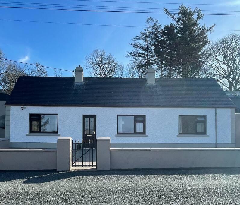 une maison blanche avec un toit noir dans l'établissement Grogagh Hill Cottage, à Sligo