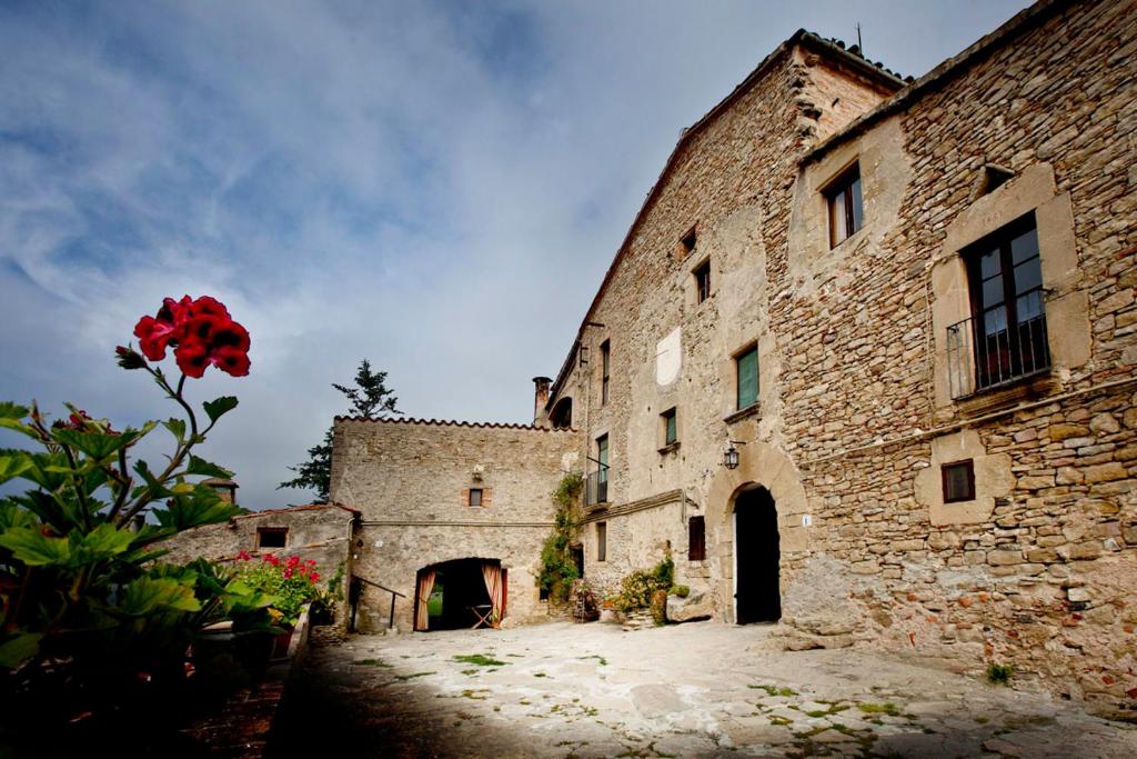 a stone building with a red flower in front of it at Brugarolas Village in Castelltersol