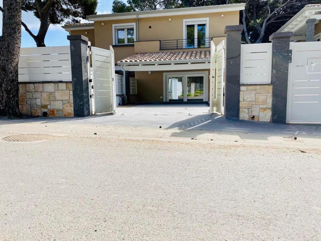 uma casa grande com portões brancos e uma entrada em Nuova Residenza dei 7 Pini a pochi passi dal mare em Porto Pino