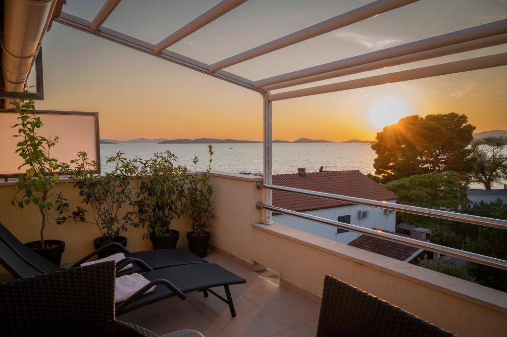 a balcony with a view of the ocean at sunset at Beach Apartments Marijana in Vodice