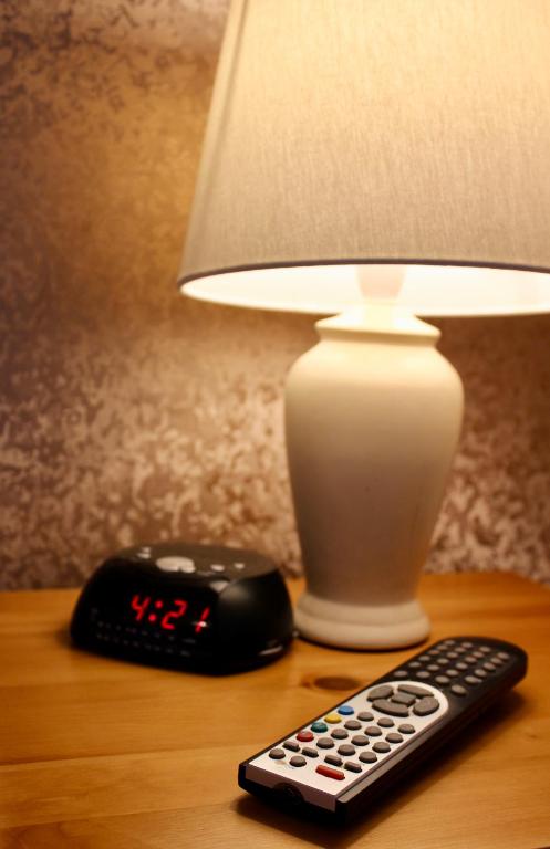 a remote control next to a lamp and a alarm clock at Bryn Noddfa in Morfa Nefyn