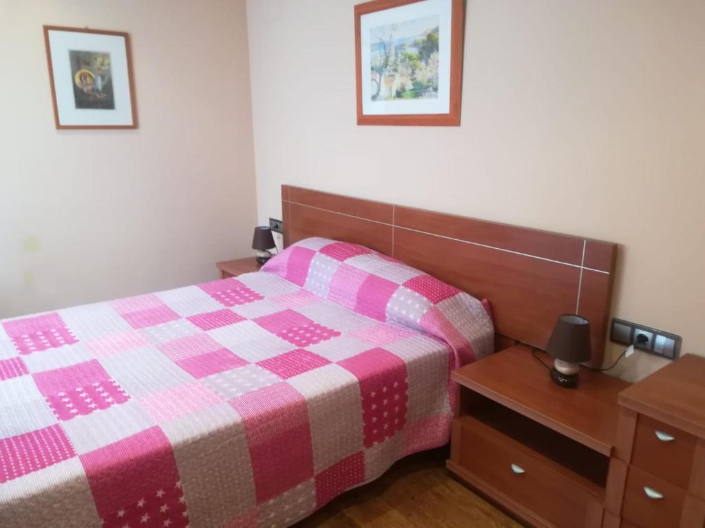 een slaapkamer met een bed met een roze en witte deken bij Apartamento con Piscina in Llança