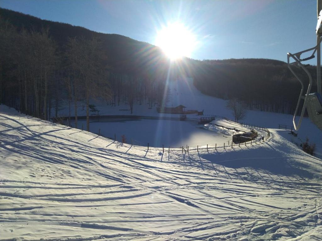 een met sneeuw bedekte skipiste met de zon op de achtergrond bij Monolocale sulle piste alle Polle in Riolunato