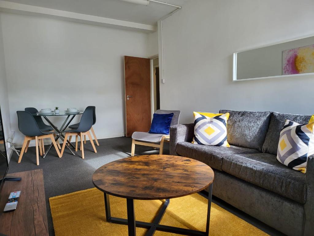 a living room with a couch and a table at Spacious, 3 Bedroom Contractor Apartment with Parking in Newport Pagnell Town Centre by Maison 19 in Milton Keynes