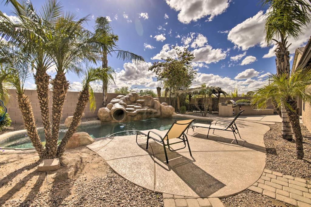 um quintal com uma piscina com duas cadeiras e palmeiras em Mesa Oasis Private Pool with Slide and Game Room! em Mesa