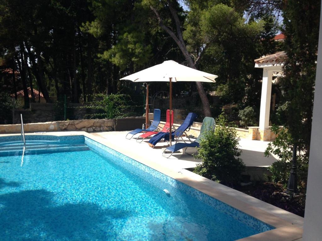 a swimming pool with chairs and an umbrella at Holiday Home Forka in Hvar