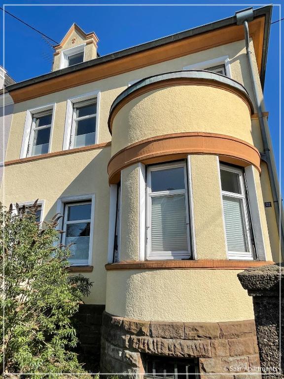 a yellow building with windows and a tower at Saar-Apartments in Merzig