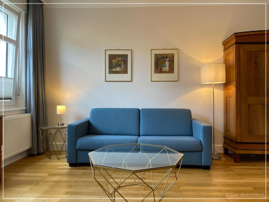 - un salon avec un canapé bleu et une table dans l'établissement Saar-Apartments, à Merzig