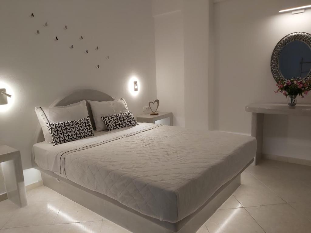 a white bedroom with a large bed and a mirror at Kiklamino Sunset Studios in Oia