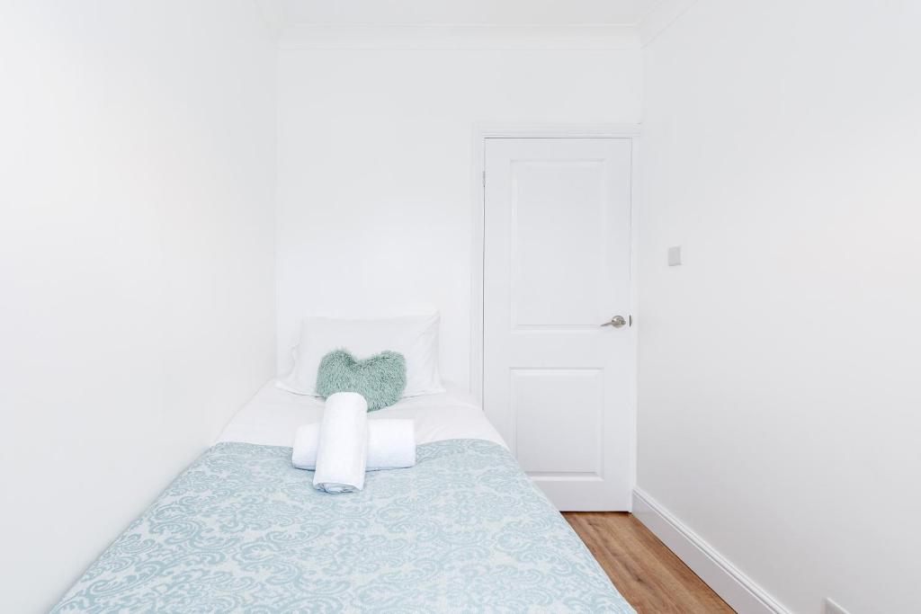 Charming 3-Bed Apartment in Romford في رومفورد: غرفة نوم بيضاء بسرير ولحاف ازرق