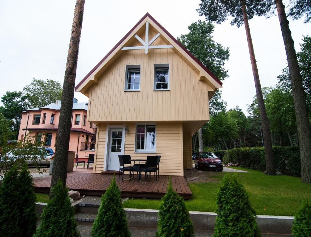a small yellow house with a table on a deck at VitaVila in Palanga