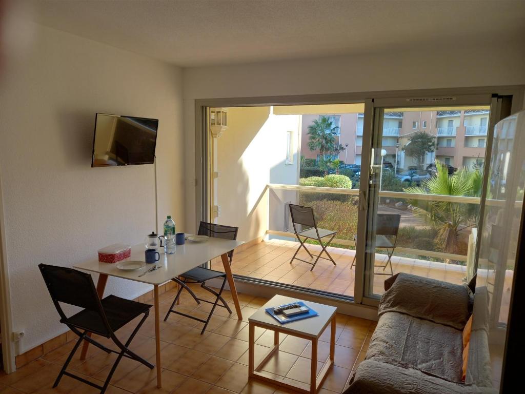 a living room with a couch and a table with chairs at Hélios 24, T2 climatisé, parking, terrasse, 500m plage in Cap d'Agde