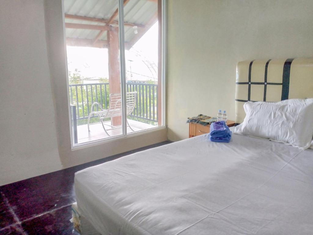 1 Schlafzimmer mit einem weißen Bett und einem Balkon in der Unterkunft Deeva Homestay Syariah RedPartner in Kota Bawah Timur