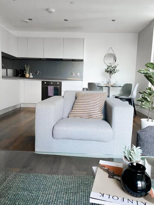 a living room with a white couch and a kitchen at The Panda - Modern 2 Bedroom Apt in Manchester City Centre in Manchester