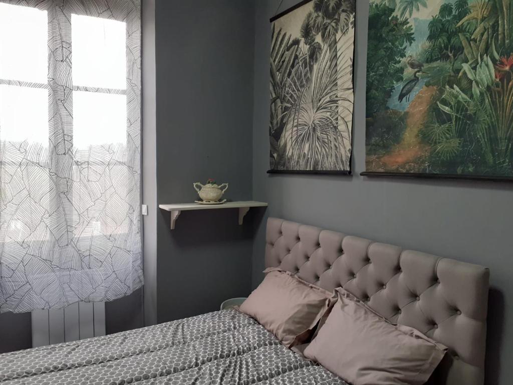 un lit dans une chambre avec deux tableaux au mur dans l'établissement Le Petit Figuier, à Villefranche-du-Périgord