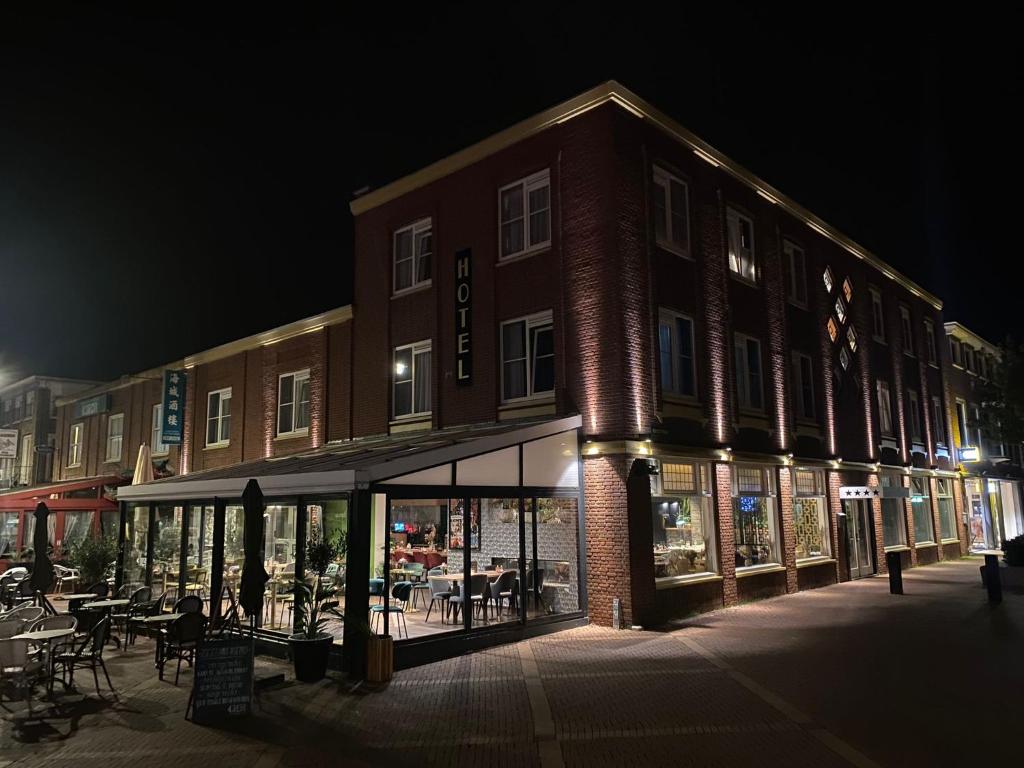 um grande edifício de tijolos com uma frente de loja à noite em Hotel Du Commerce em Oostburg