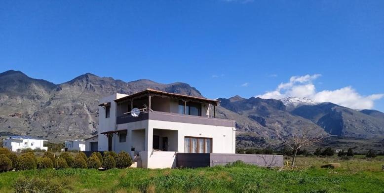 a white house in a field with mountains in the background at Ledakis House in Frangokastello